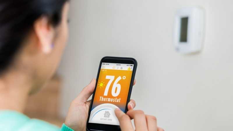 woman controlling wireless thermostat
